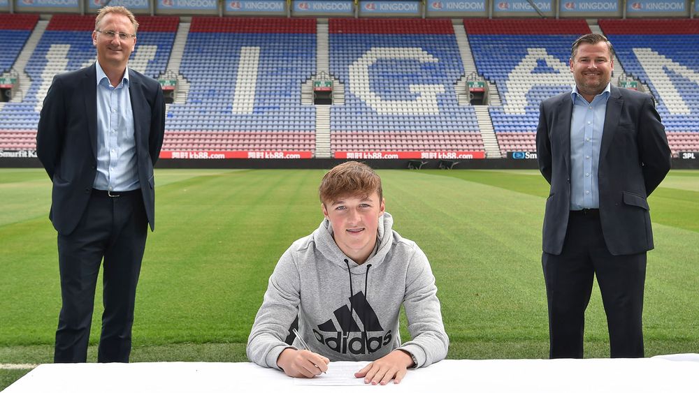 Alfie signs his Latics contract with chief executive Jonathan Jackson and academy manager Gregor Rioch